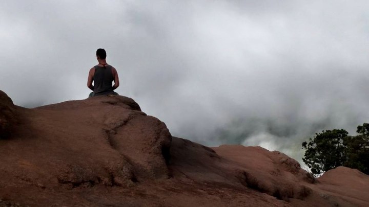 man on bluff meditating