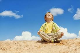 little boy meditating on top of the world
